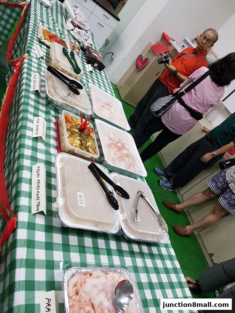 A table displaying various food items in catering trays, with people observing.