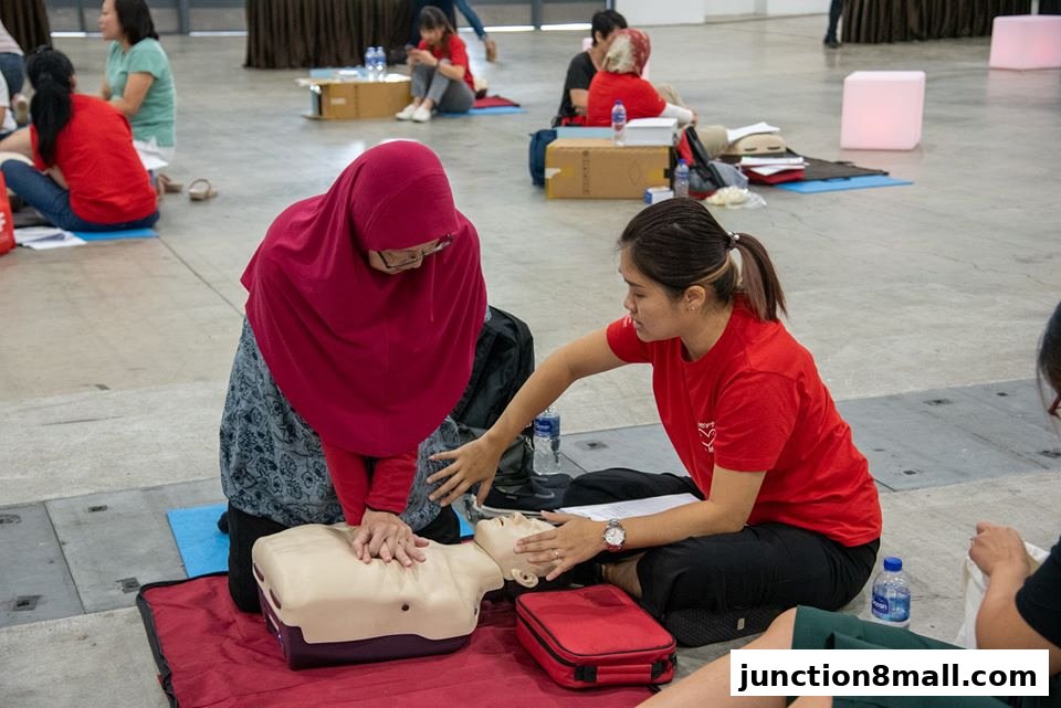 Two women practice CPR on a dummy during a health workshop.