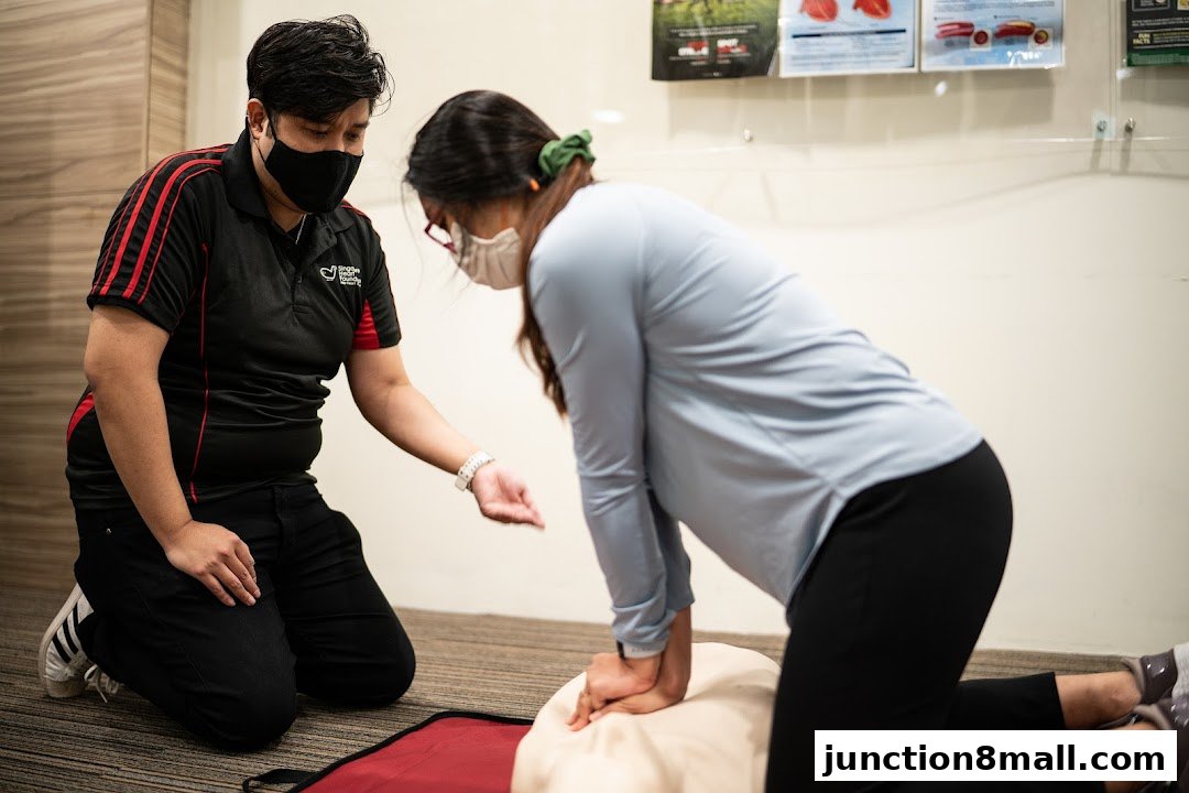 An instructor teaches CPR techniques on a dummy to a participant.