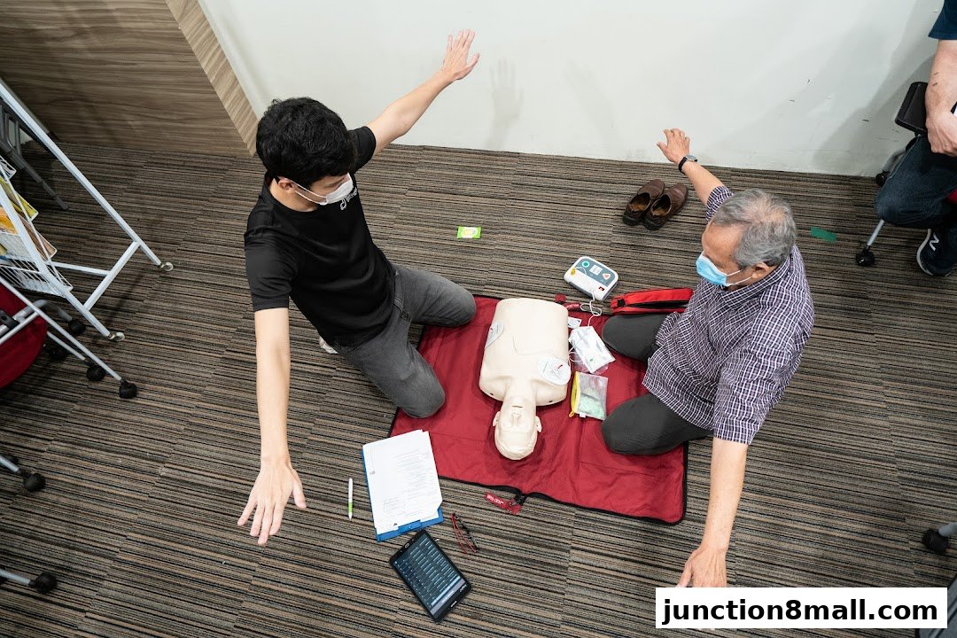 Two people practice CPR on a dummy with medical equipment laid out.