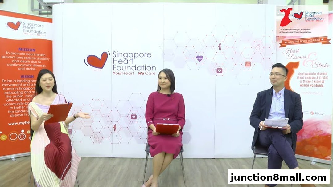 Three people are presenting information about heart health in front of a backdrop with the Singapore Heart Foundation logo.