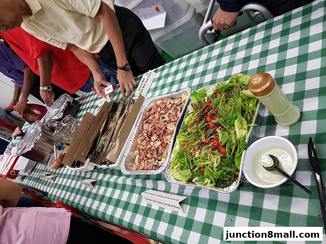 A table laden with various food dishes, including salads and meats, covered with a green and white checkered cloth.