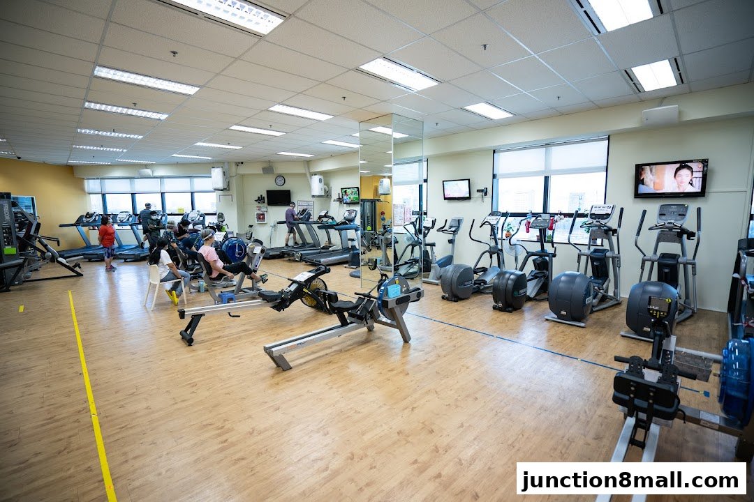 Interior of a gym with various cardio machines and people exercising.