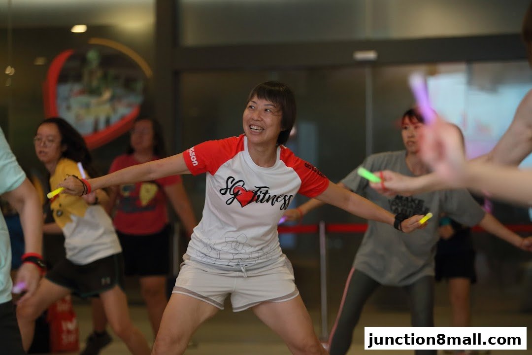 A group of people participating in a fitness class, holding glow sticks and exercising.