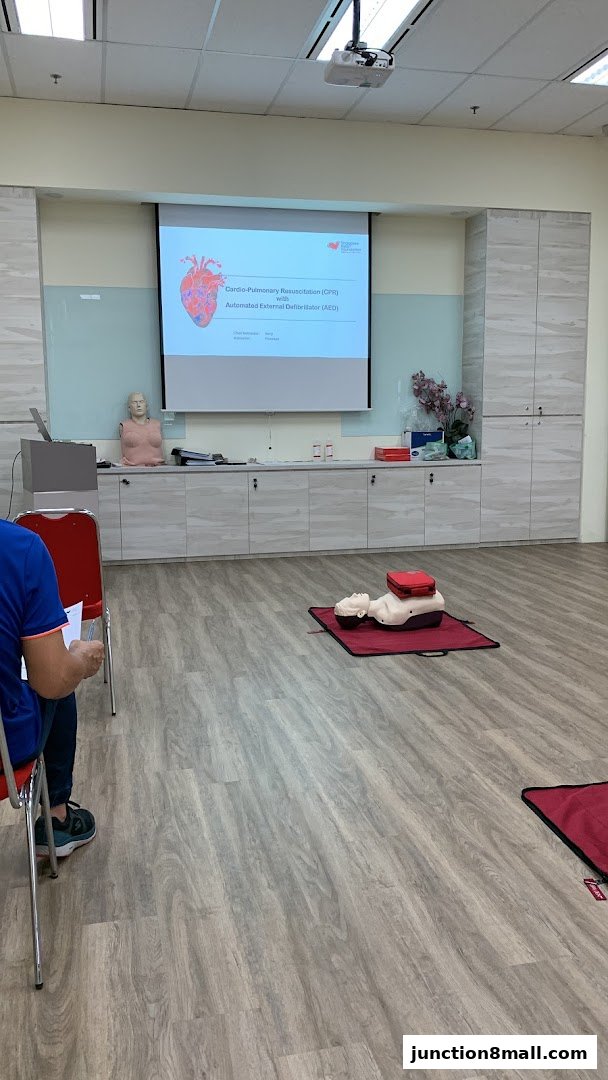 A training room with a projector screen displaying CPR and AED information, and mannequins for practice.