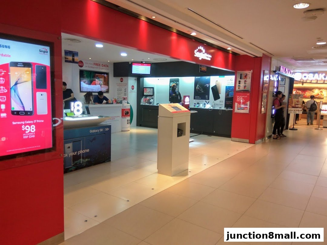 A Singtel Exclusive Retailer shop front with displays of smartphones and promotional signage.