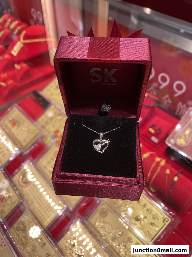 A heart-shaped diamond pendant necklace displayed in a red jewelry box.