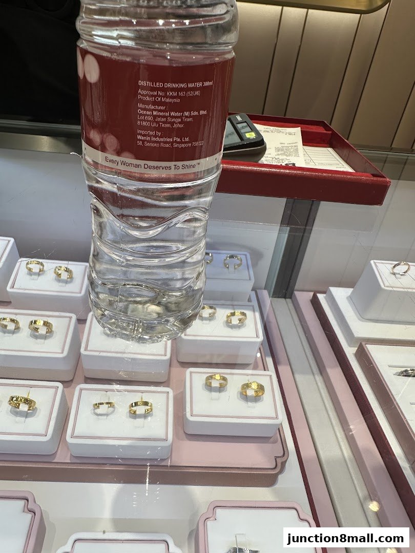 A display of gold rings in a jewelry store, with a water bottle in the foreground.