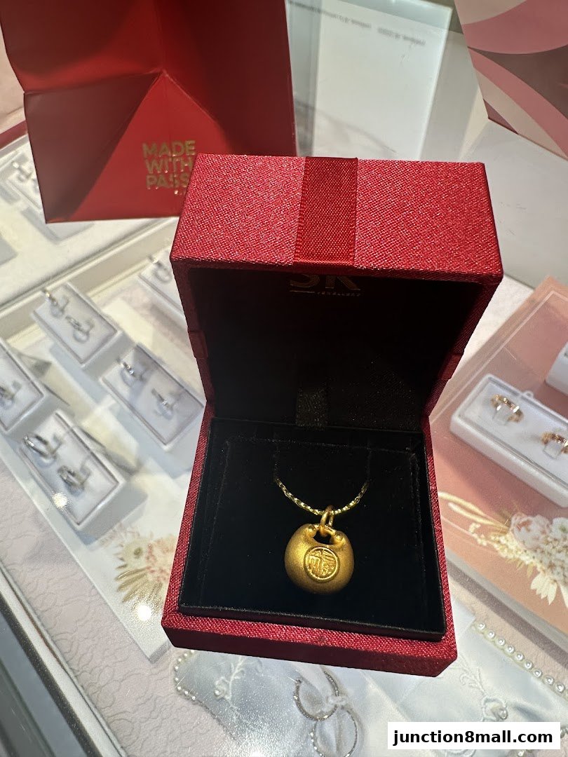 A gold pendant with Chinese characters in a red jewelry box, with other jewelry displayed.