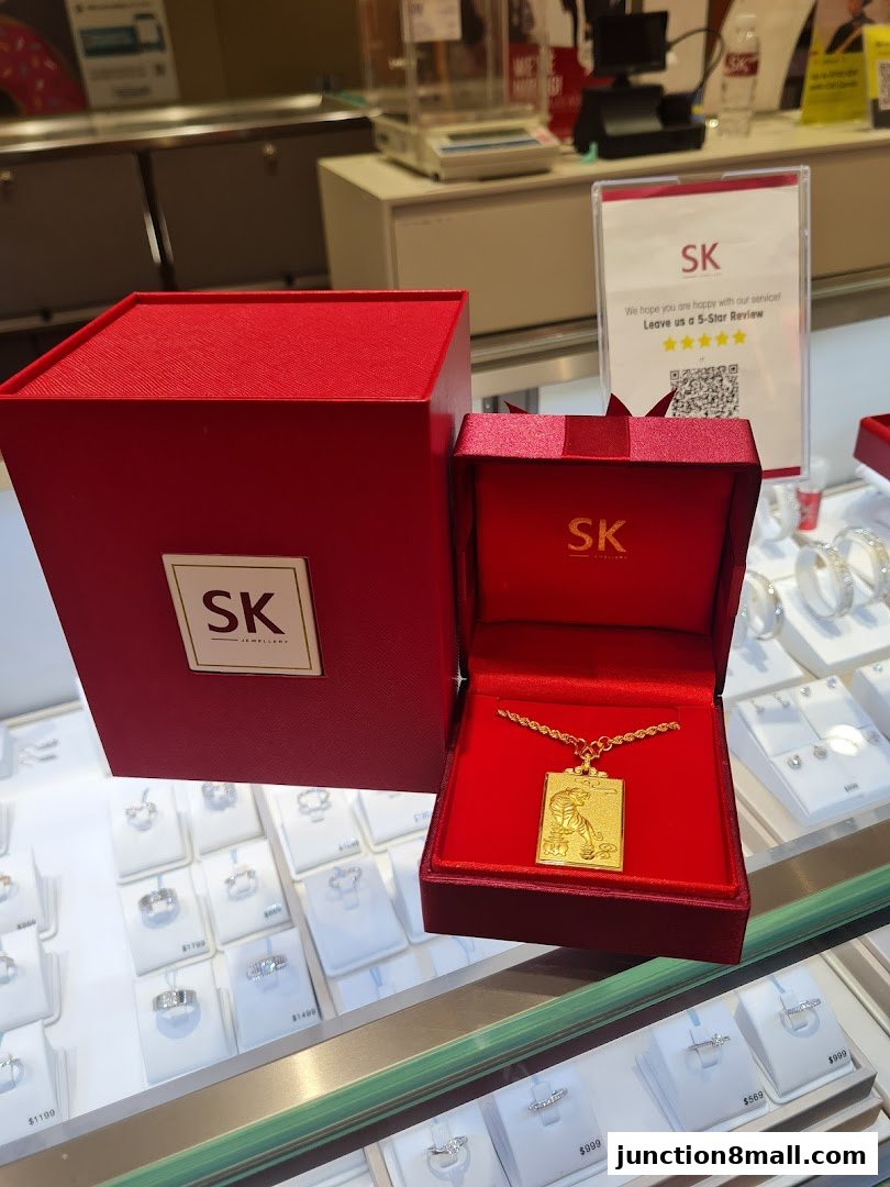 A gold pendant with a tiger design in a red jewelry box, displayed in a jewelry store.
