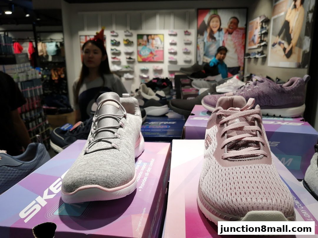 Skechers store interior showcasing various athletic shoes and a staff member.
