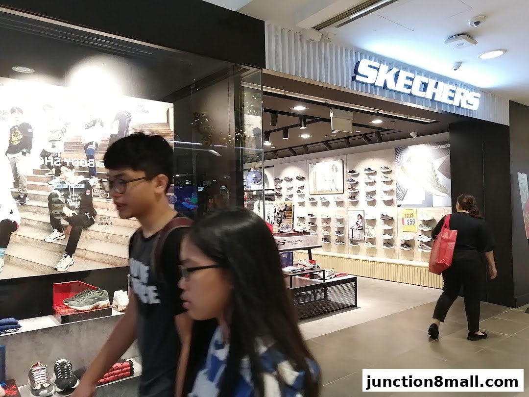 The Skechers store entrance with shoes displayed and people walking by.