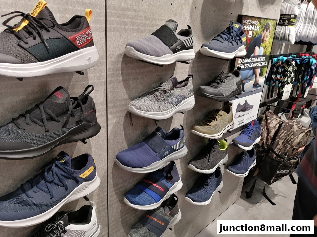 A display of Skechers athletic shoes and socks on a wall.
