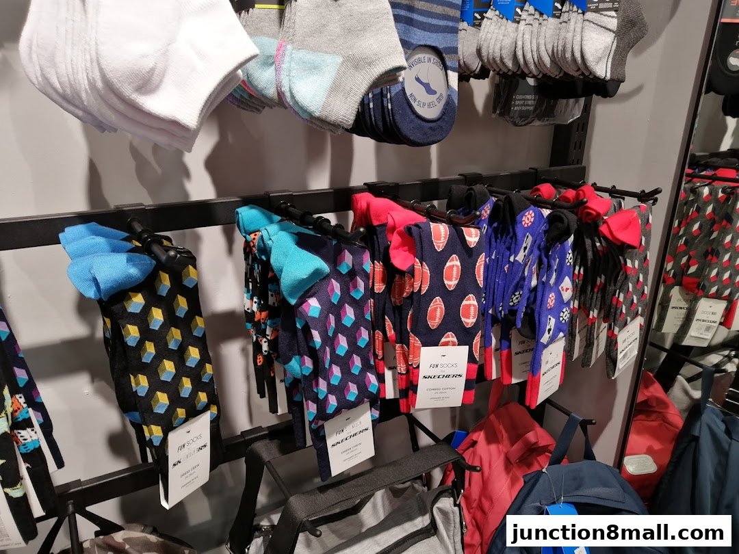 A display of colorful and patterned socks, along with backpacks, at a Skechers store.