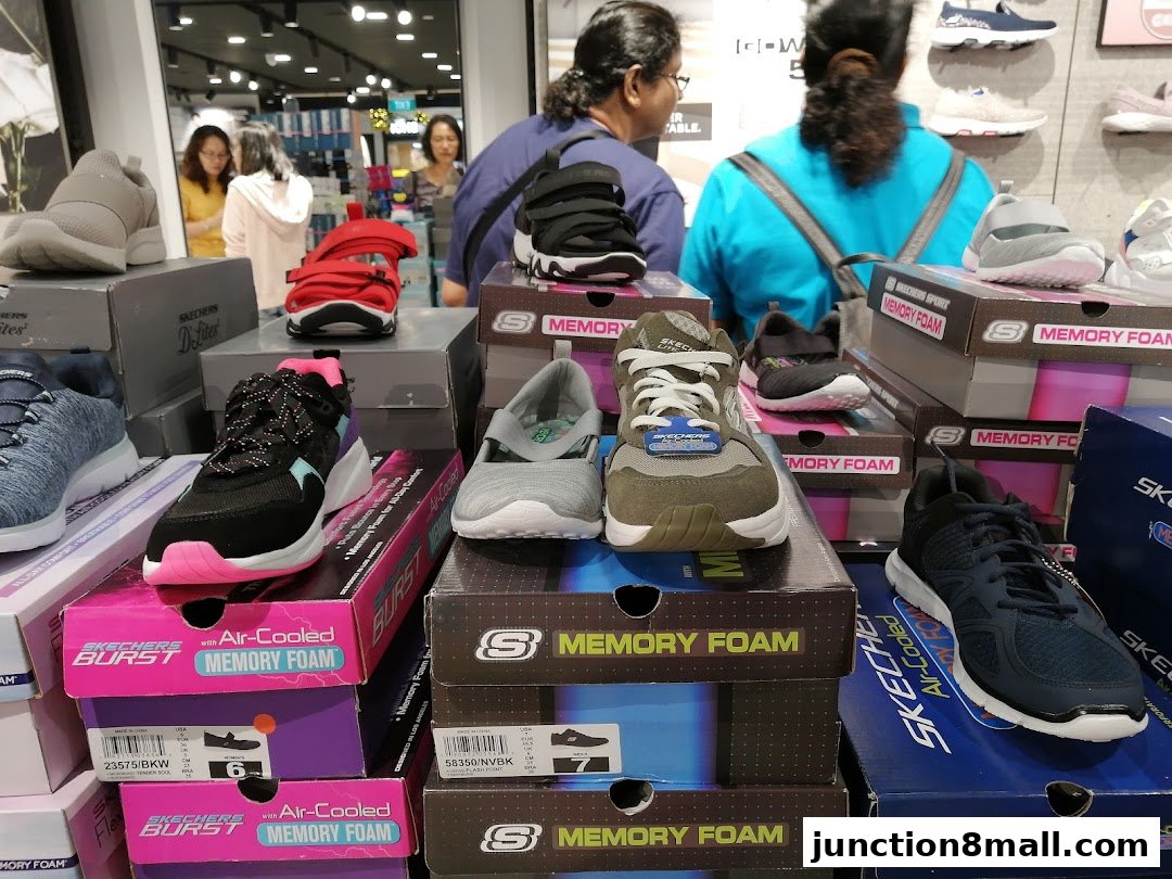 A display of various Skechers shoes, including sneakers and sandals, on boxes inside a store.