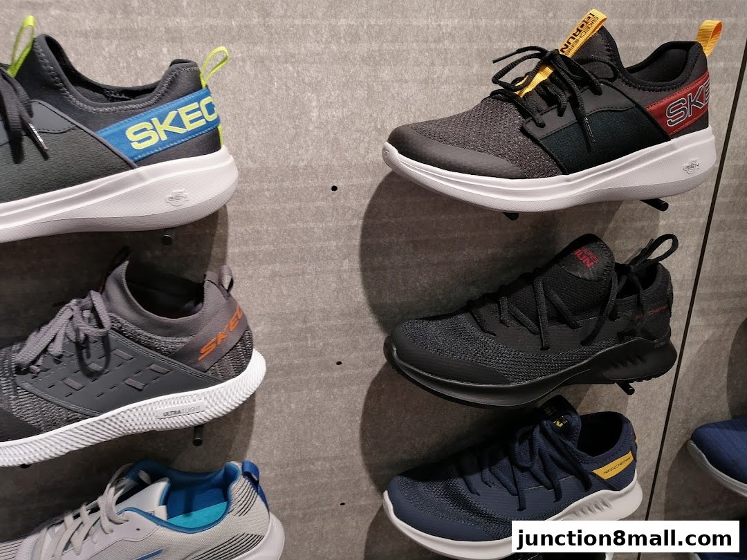 A display of various Skechers athletic shoes on a textured wall.