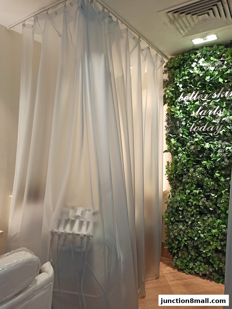 Interior of a beauty salon with treatment equipment behind sheer curtains and a green wall.