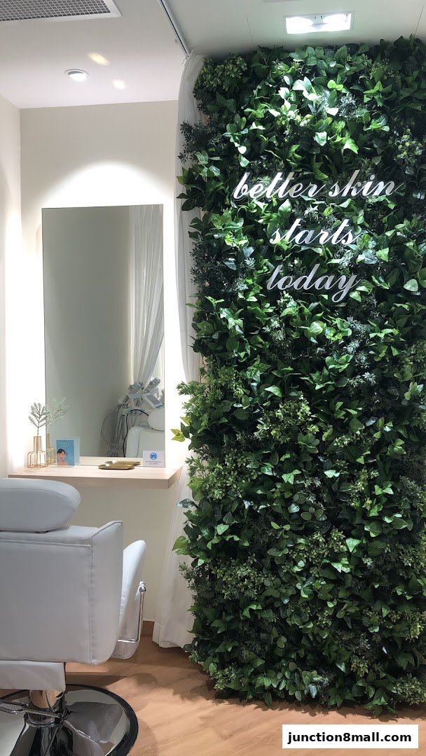 A modern beauty salon interior with a white chair, mirror, and a lush green living wall.