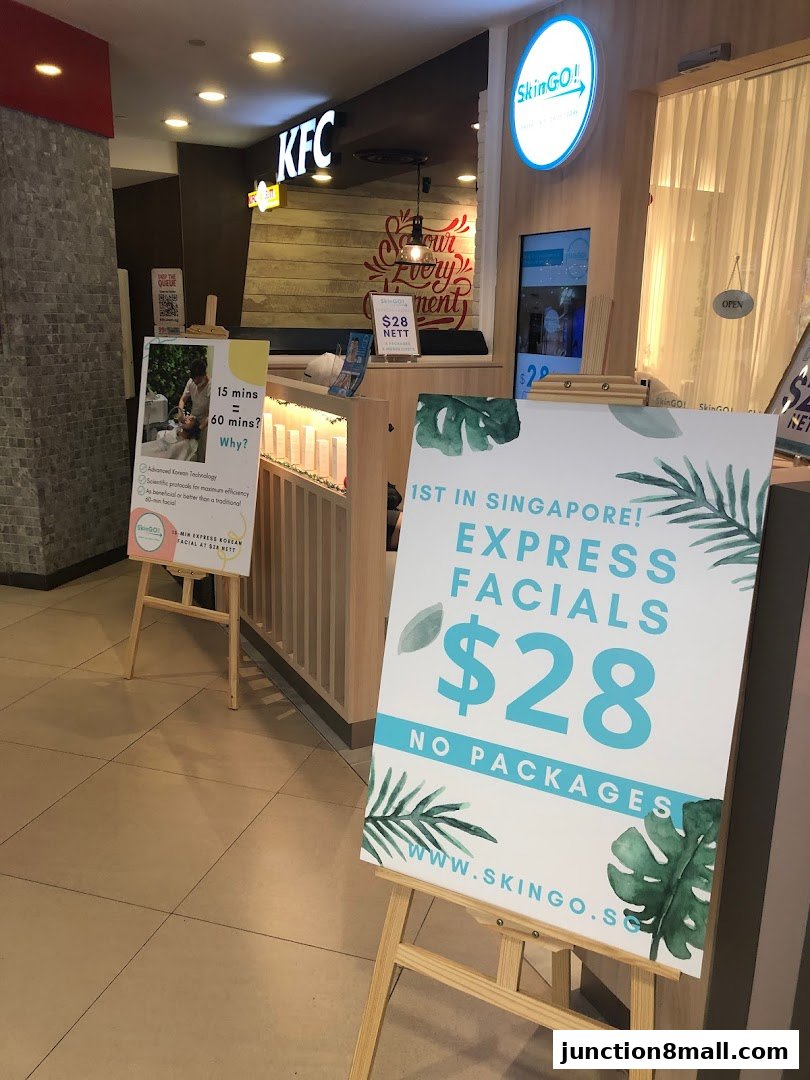SkinGO! shop front with promotional signs for express facials and a nearby KFC.