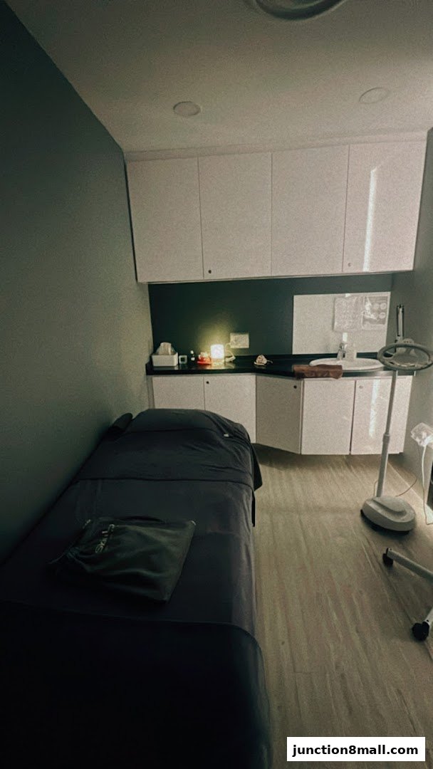 A treatment room with a massage bed, sink, and storage cabinets.