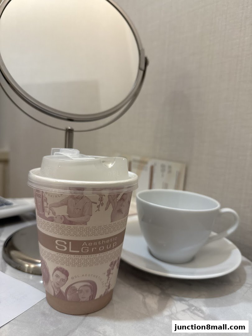 A branded cup and an empty teacup on a table with a mirror in the background.