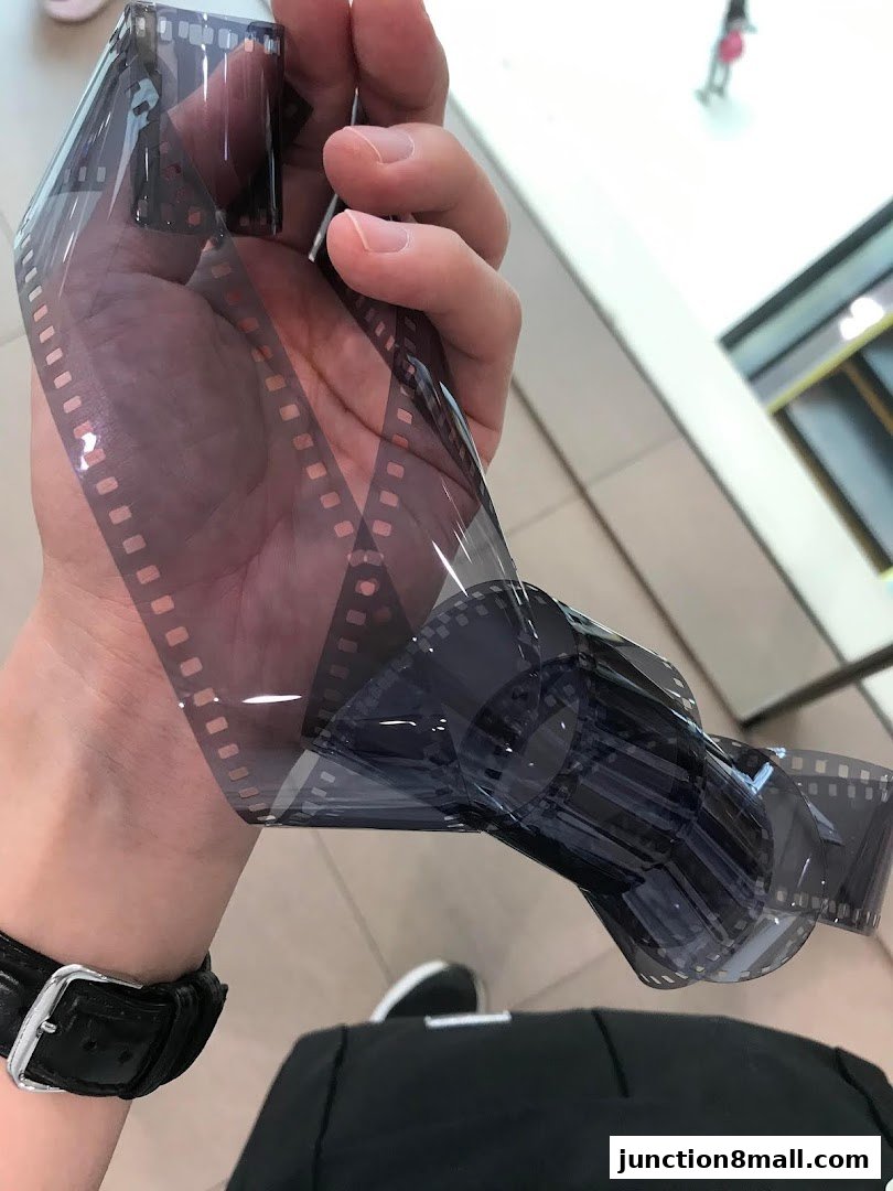 A hand holds a roll of developed film, showcasing the classic photographic process.