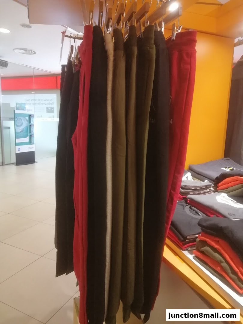 A rack of colorful sweatpants and folded t-shirts displayed in a retail store.