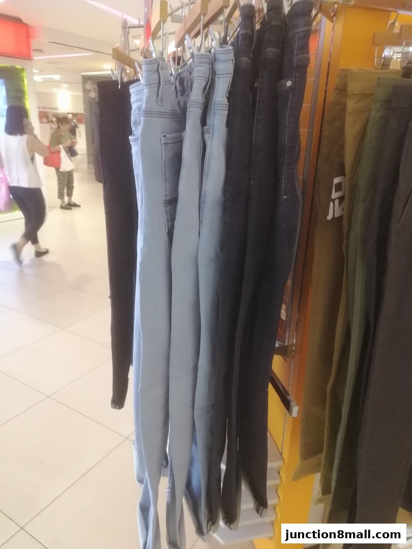 A rack of various colored jeans displayed in a retail store.
