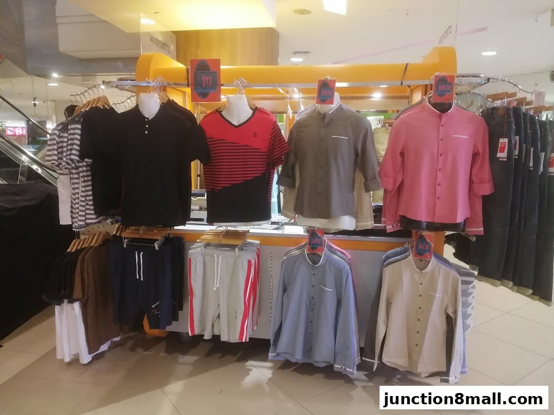 A display of men's casual wear, including shirts and shorts, on mannequins and racks.