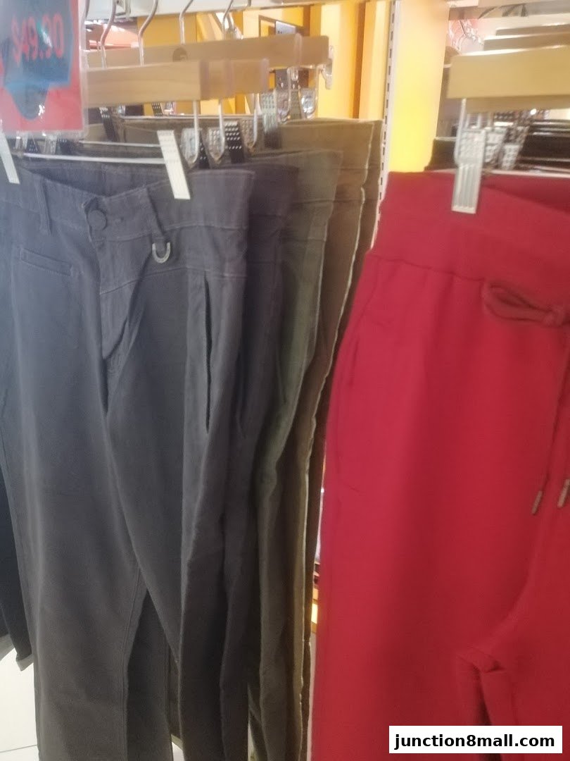 Pants in various colors, including grey, olive green, and red, displayed on hangers.