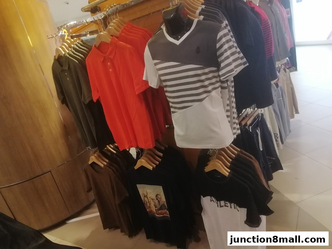 A display of various t-shirts and polo shirts hanging on racks in a retail store.
