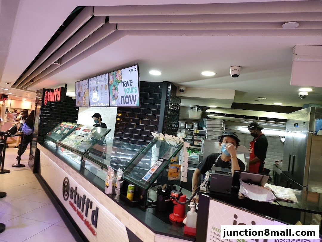 Staff members working behind the counter at a food establishment called Stuff'd.