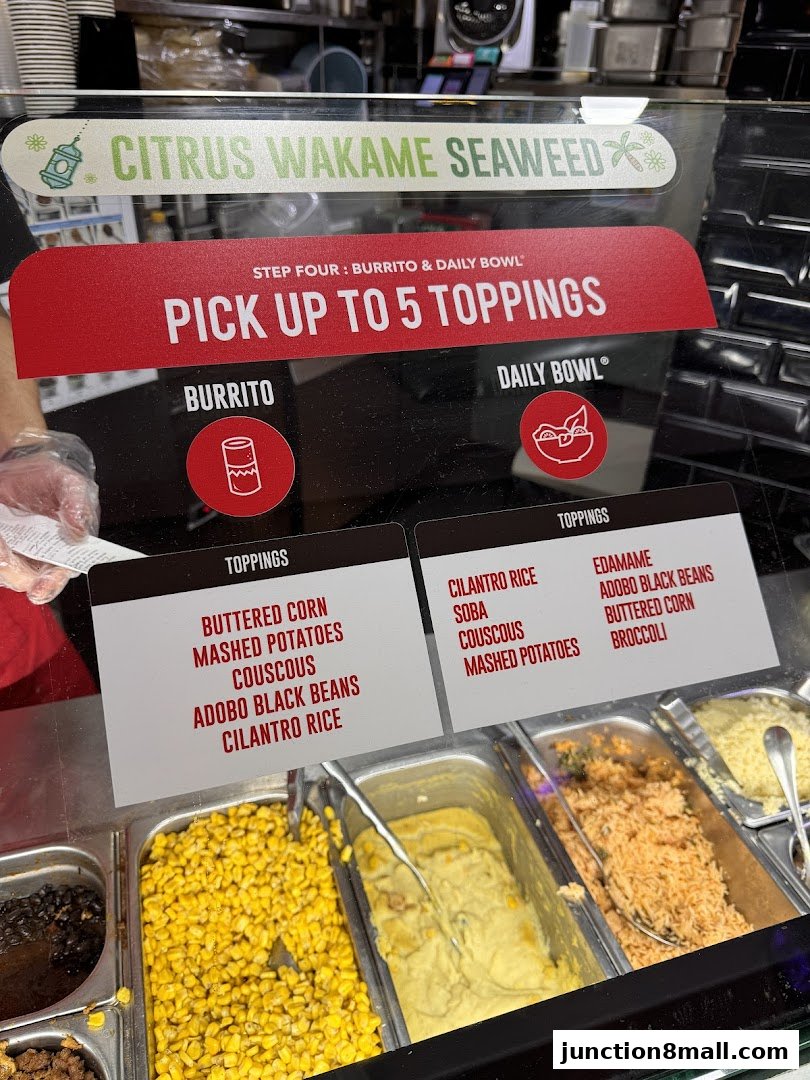 A display of fresh toppings for burritos and bowls at a restaurant.