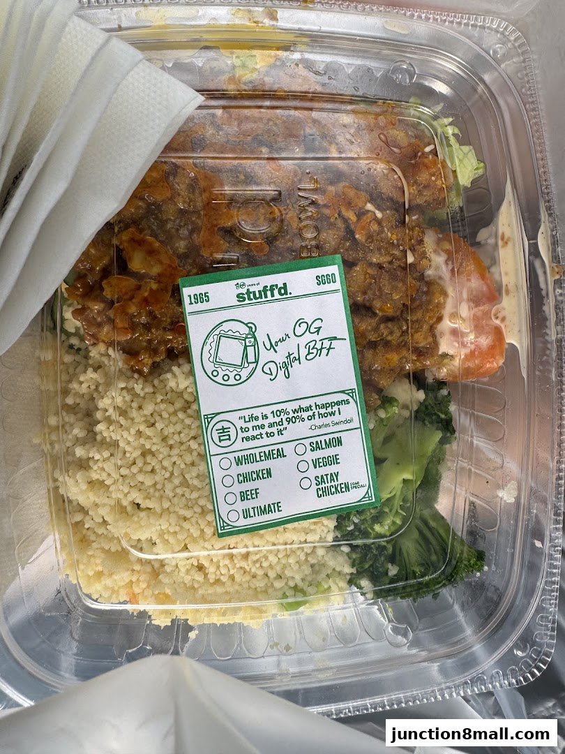 A clear plastic container filled with a meal, featuring couscous, broccoli, and a meat topping.
