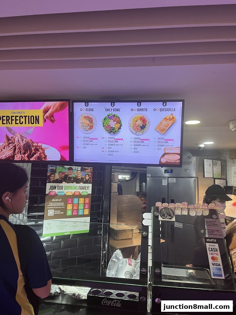 A digital menu board displays various food options like kebabs, bowls, burritos, and quesadillas.