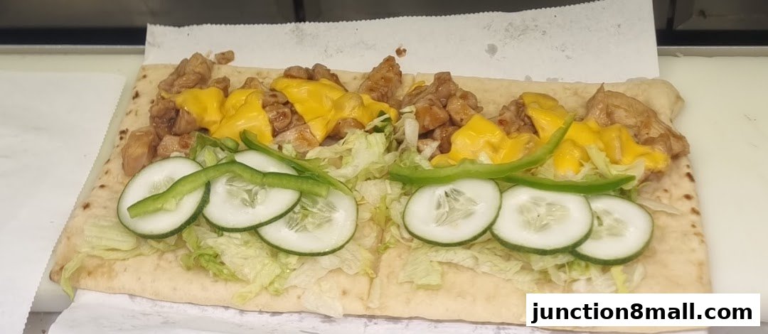 A Subway sandwich with chicken, cheese, lettuce, cucumber, and green peppers on flatbread.