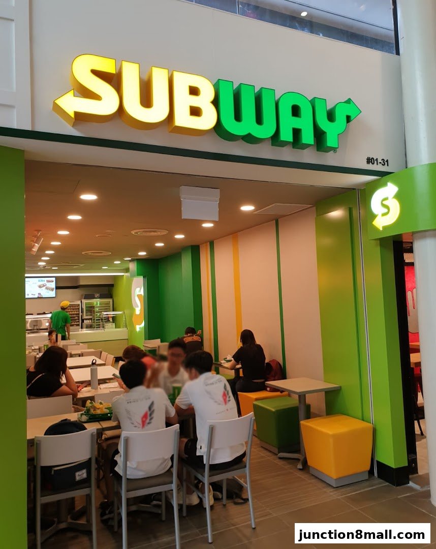 People dining inside a Subway restaurant with its signature green and yellow branding.