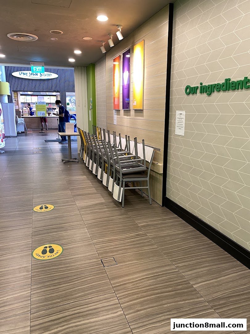 A hallway leading to a food establishment with chairs stacked and social distancing markers on the floor.