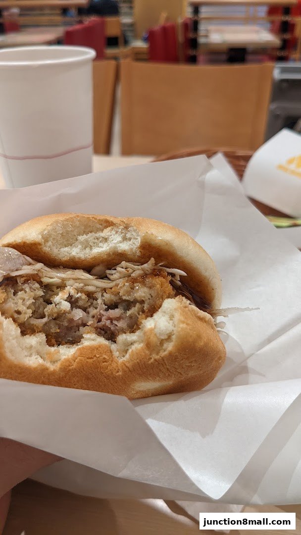 A close-up of a partially eaten sandwich with a white cup in the background.