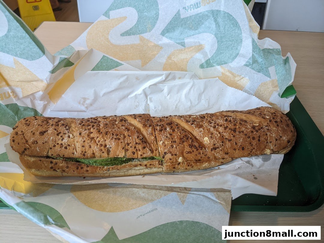 A Subway sandwich on a tray, wrapped in branded paper.