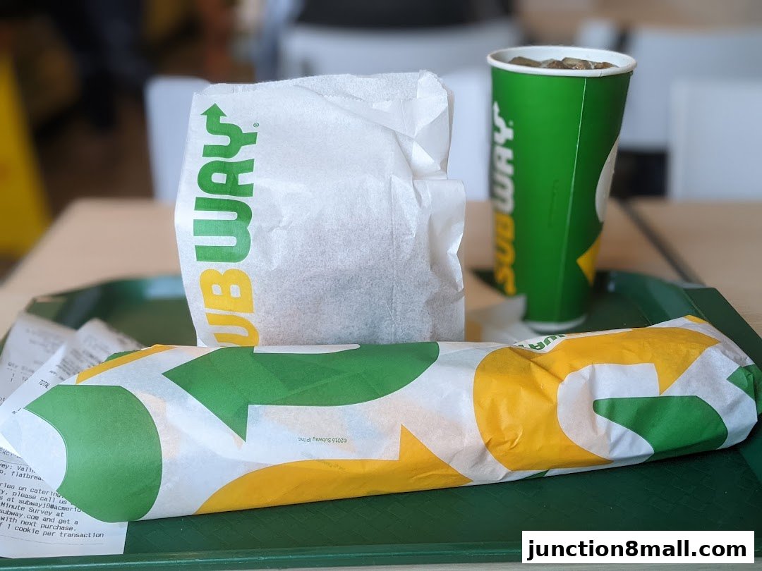 A Subway sandwich, drink, and bag on a green tray.