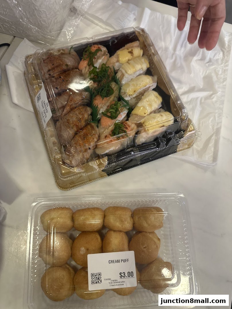 A close-up of two takeaway containers, one with assorted sushi and the other with cream puffs.