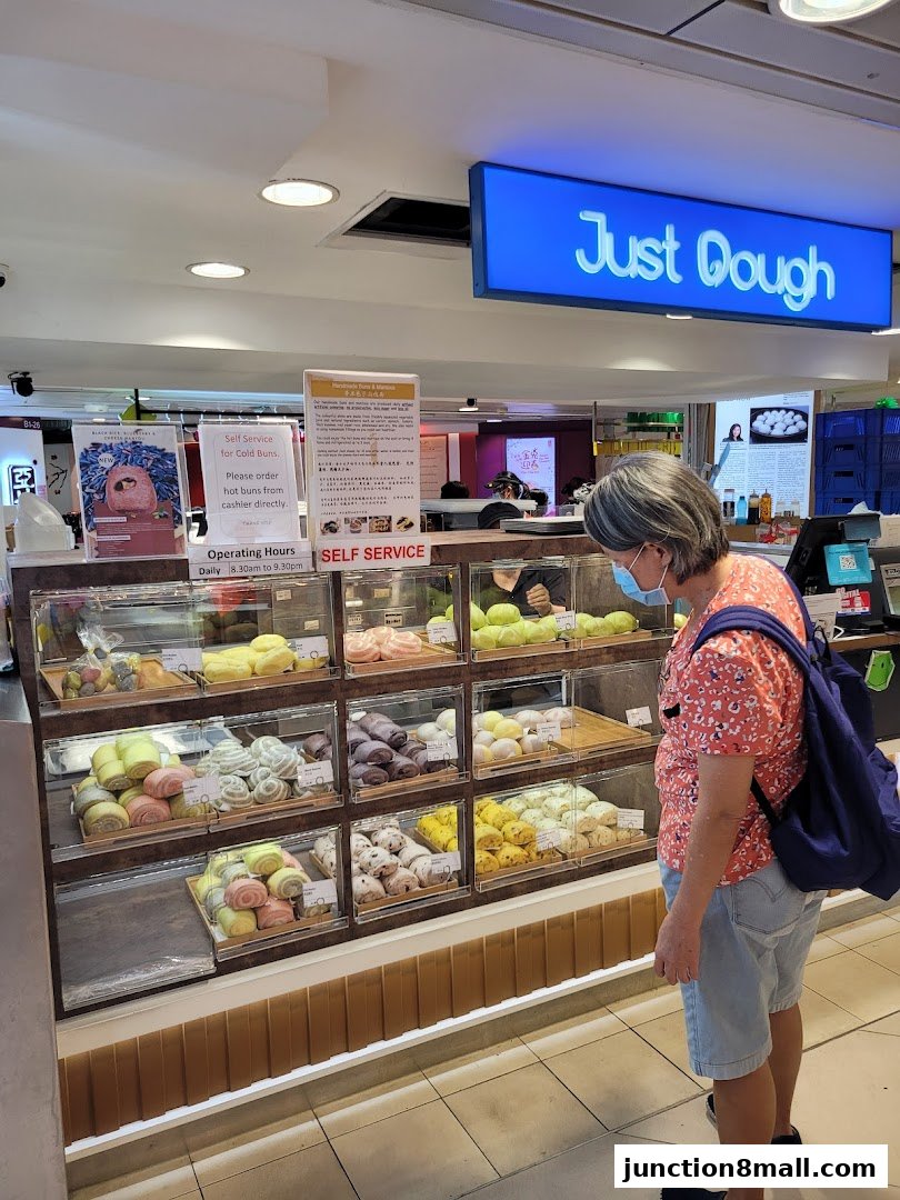 A customer browses a display of colorful buns at a bakery counter.