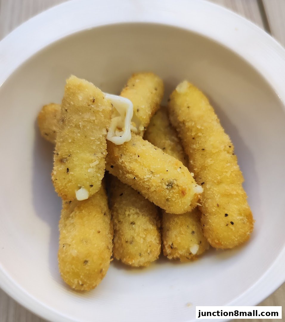 A close-up shot of crispy, golden-brown mozzarella sticks served in a white bowl.