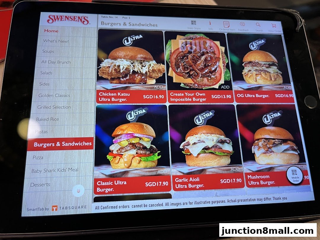 A tablet displaying the Swensen's menu with various burgers and sandwiches.