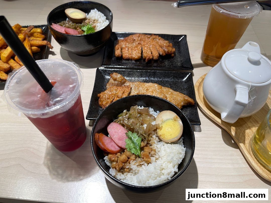 A table laden with Taiwanese dishes, including rice bowls, fried pork, and drinks.