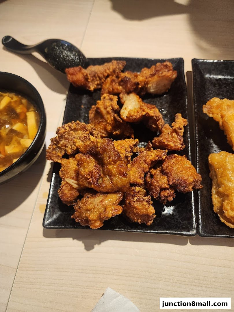 Plates of crispy fried chicken and a bowl of soup are on a table.