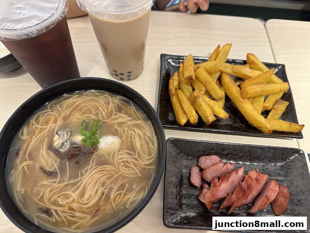 A table with Taiwanese food including oyster noodles, fries, sausage, and bubble tea.