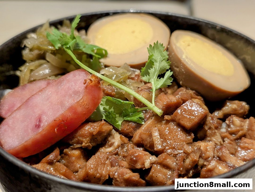 A close-up of a Taiwanese braised pork rice bowl with eggs and sausage.