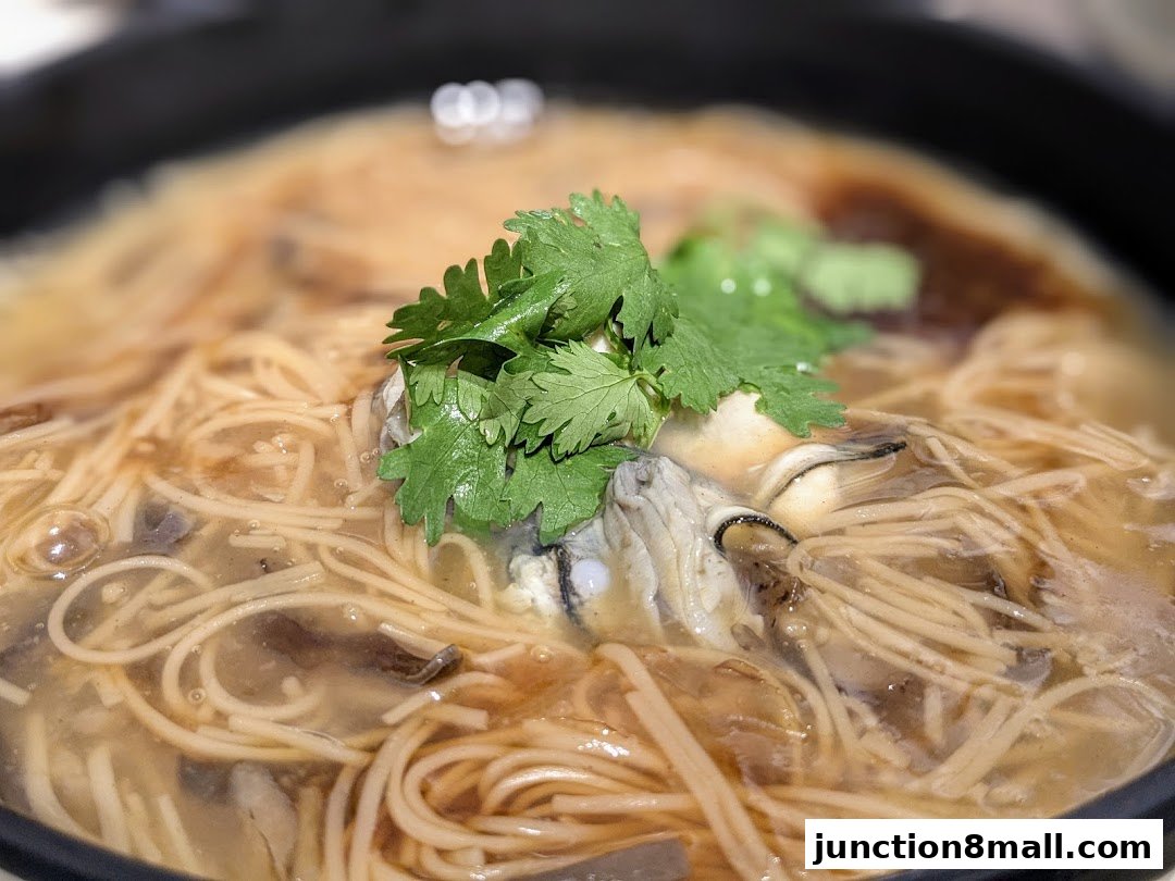 A close-up shot of a steaming bowl of oyster vermicelli soup, garnished with fresh cilantro.